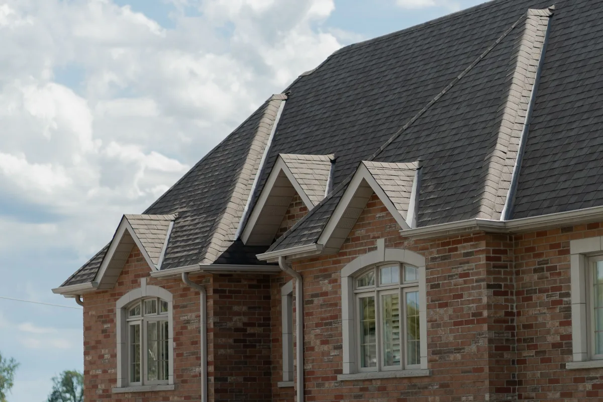 After: brick home with a crisp new dark shingle roof