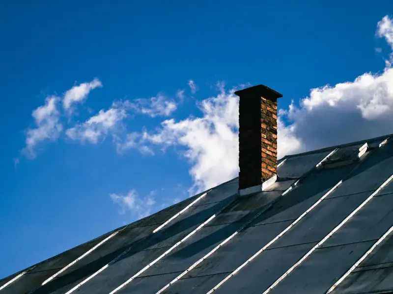 Dark standing-seam metal roof with a brick chimney in Allen