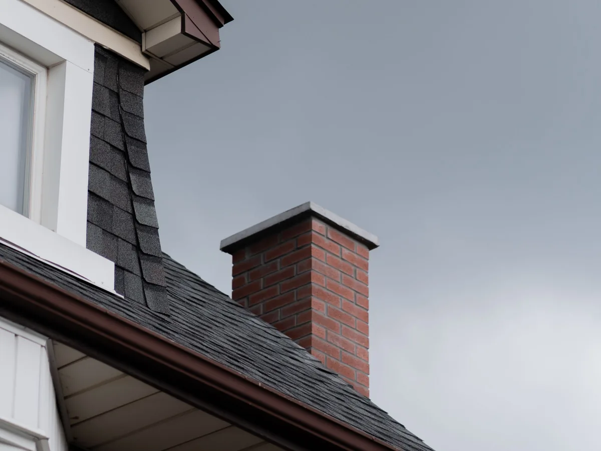 Roof eave showing new gutter, fascia board and soffit beneath asphalt shingles