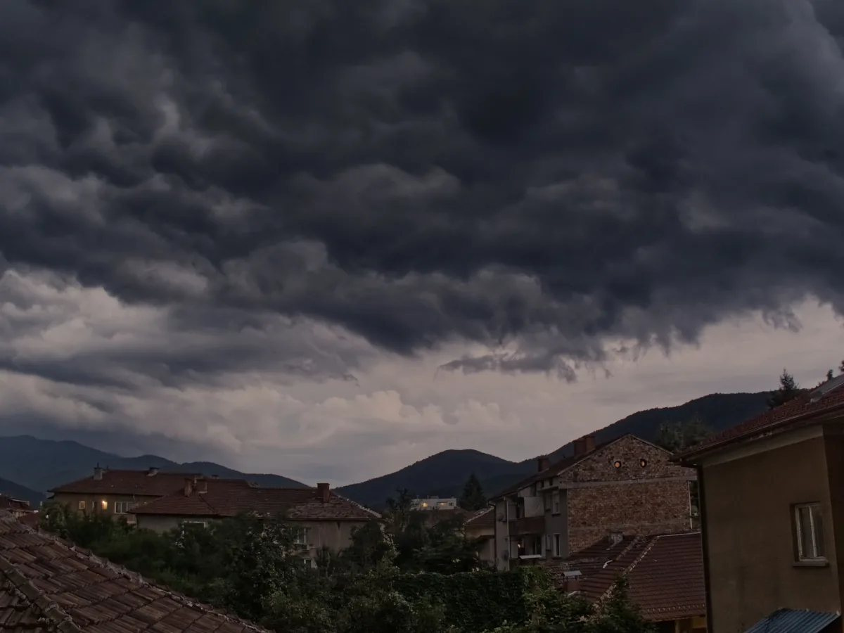 Dark storm clouds gathering over a row of residential rooftops